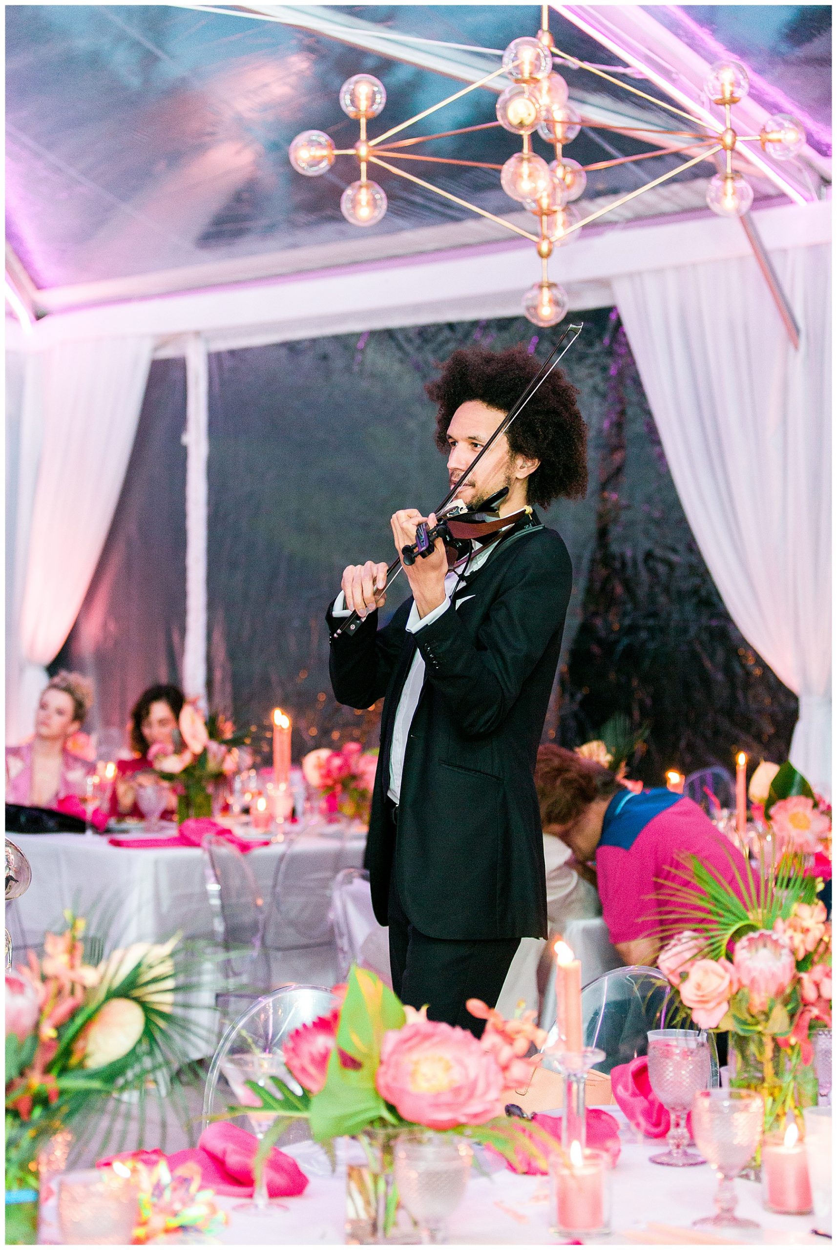 a violinist entertaining people at a party under a tent